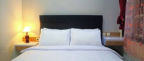 Una cama bien tendida con sábanas blancas, una lámpara de noche y un enchufe en la mesita de noche.