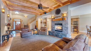 A spacious living room with leather sofas, a stone fireplace, and a wooden ceiling. - Prime Location Near Skiing | Luxe All-Season Retreat by AvantStay (Truckee)