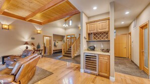 A spacious living area with a wooden ceiling, a leather sofa, and a kitchen with wooden cabinets. - Prime Location Near Skiing | Luxe All-Season Retreat by AvantStay (Truckee)