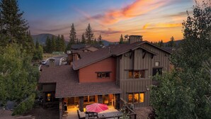 A modern two-story house with a patio area featuring outdoor furniture and a red umbrella. - Prime Location Near Skiing | Luxe All-Season Retreat by AvantStay (Truckee)