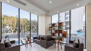 A modern interior with large windows, a sofa, a bookshelf, and a small table. - Mai Peng Hotel (Qingguo Lane, Changzhou Railway Station) (Changzhou)