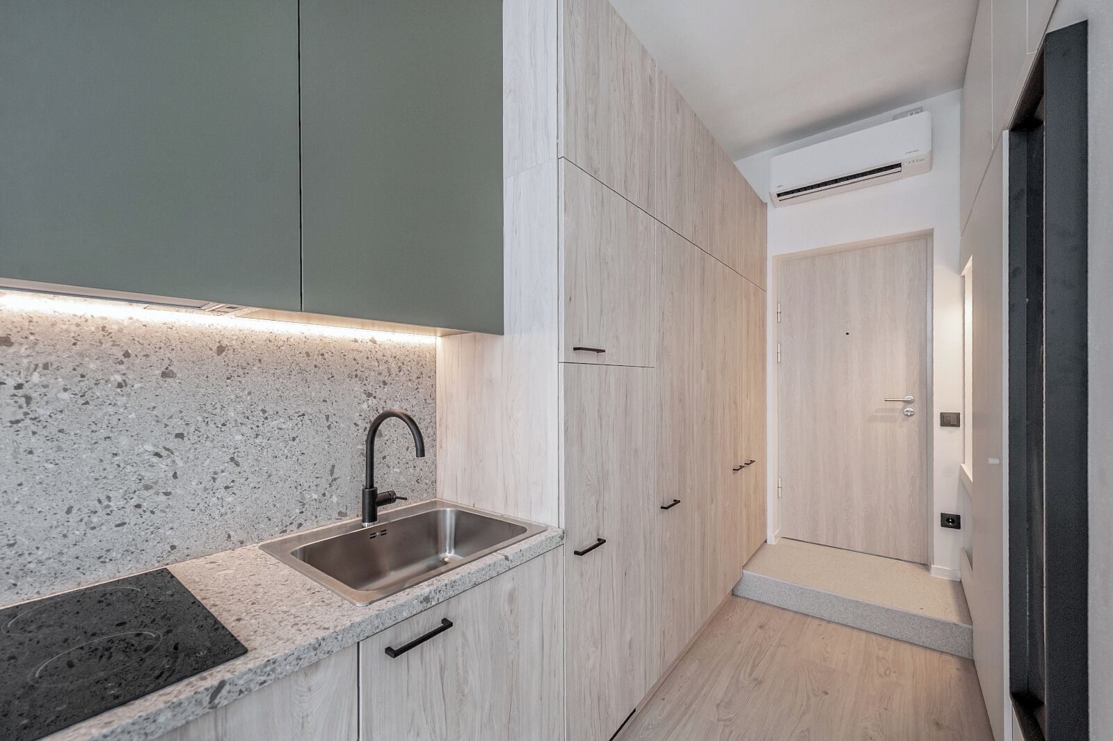 Una cocina moderna con encimera de granito, pileta de acero inoxidable y muebles de madera.