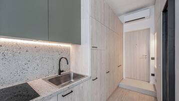 A modern kitchen with a granite countertop, stainless steel sink, and wooden cabinets.