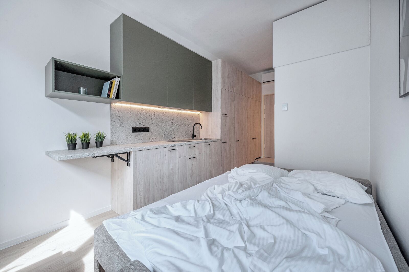 Una habitación compacta con cama, una kitchenette pequeña y un armario empotrado.