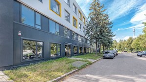 Un edificio moderno con amplios ventanales y una zona de estacionamiento.