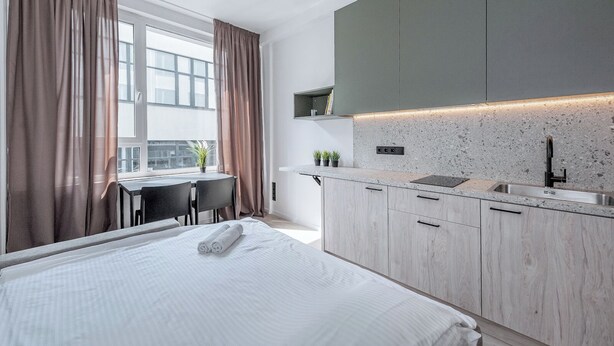 Una habitación de hotel moderna con cama, escritorio y kitchenette.