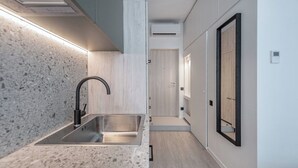 Una cocina moderna con un lavamanos de acero inoxidable, un grifo negro y una encimera clara con vetas.