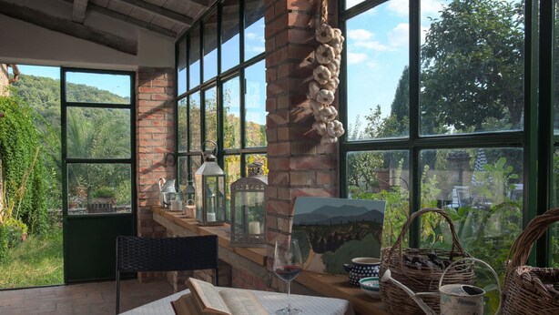 A cozy reading nook with a large window, a brick fireplace, and rustic decor. - Tuscany Country Retreat for 12 at Santo Stefano Winery near Greve in Chianti (Firenze)