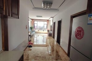 A hallway with a marble floor, a refrigerator with a red logo, and a door with a circular emblem.