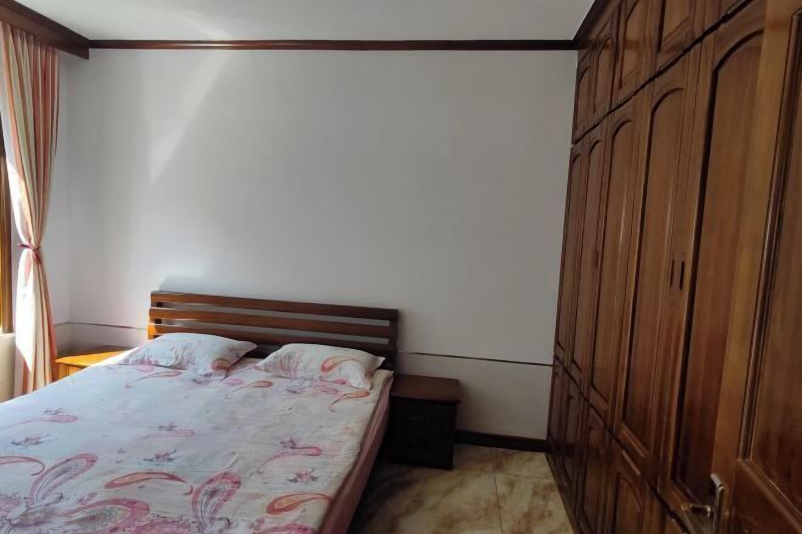 A bedroom with a wooden bed, a nightstand, and a wardrobe.