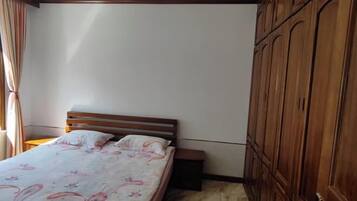 A bedroom with a wooden bed, a nightstand, and a wardrobe.