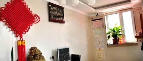 A reception area with a reception desk, a wall clock, a potted plant, and a bulletin board.