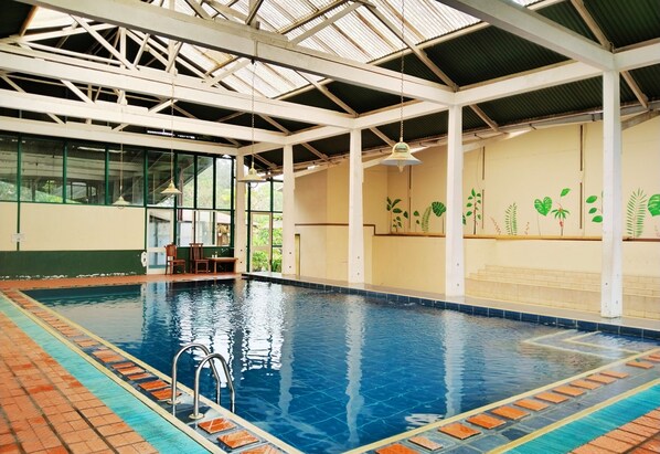 An indoor swimming pool with clear blue water, surrounded by a tiled deck.