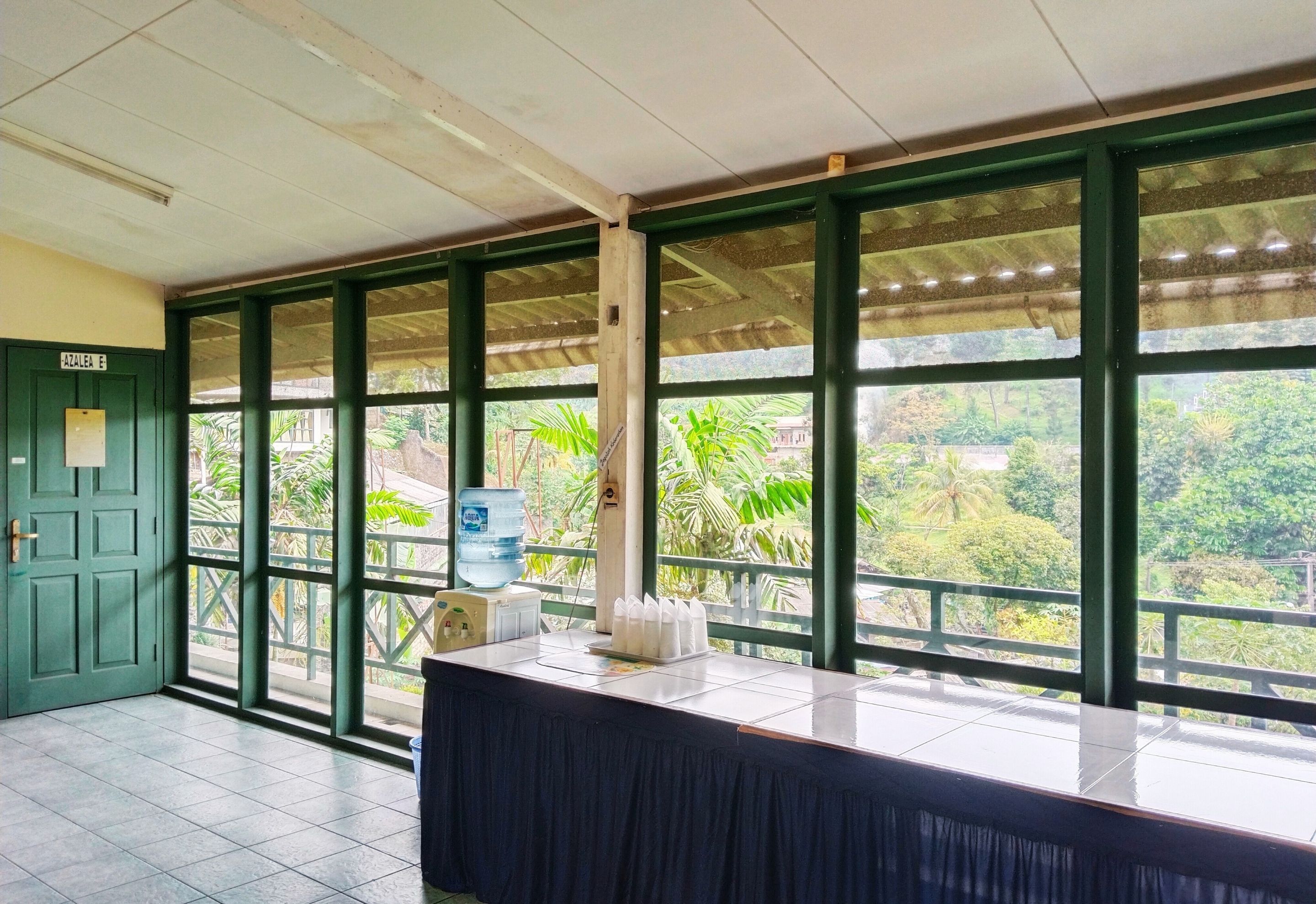 Una habitación con ventanas amplias, un dispensador de agua y una mesa con mantel negro.