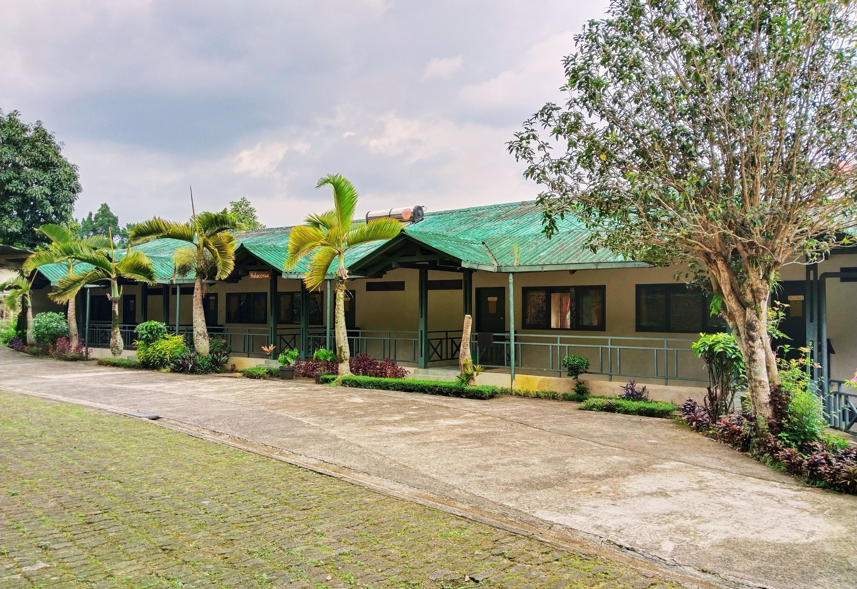 A row of single-story buildings with green roofs and a paved walkway.