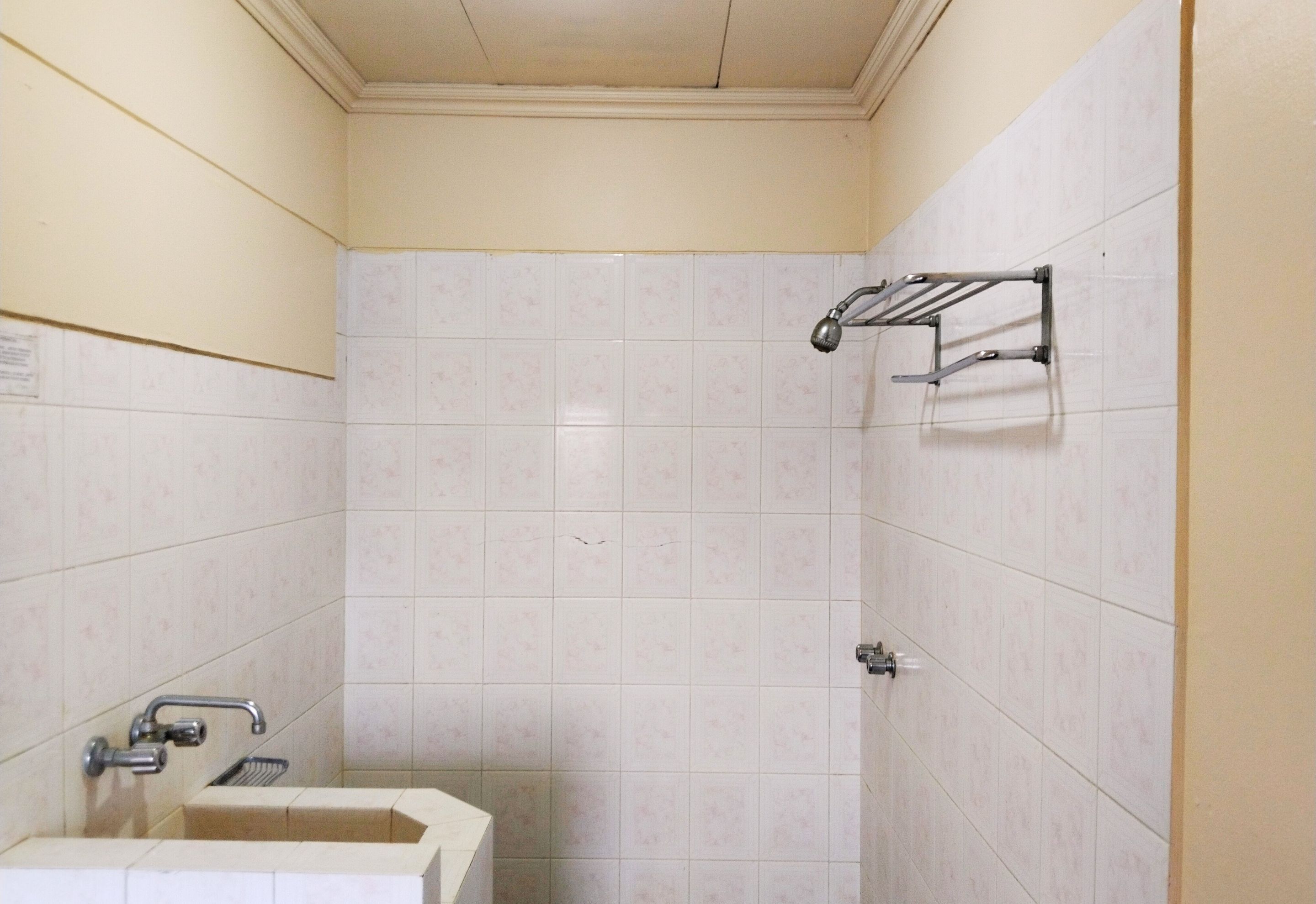 A small, tiled bathroom with a sink, a shower, and a towel rack.