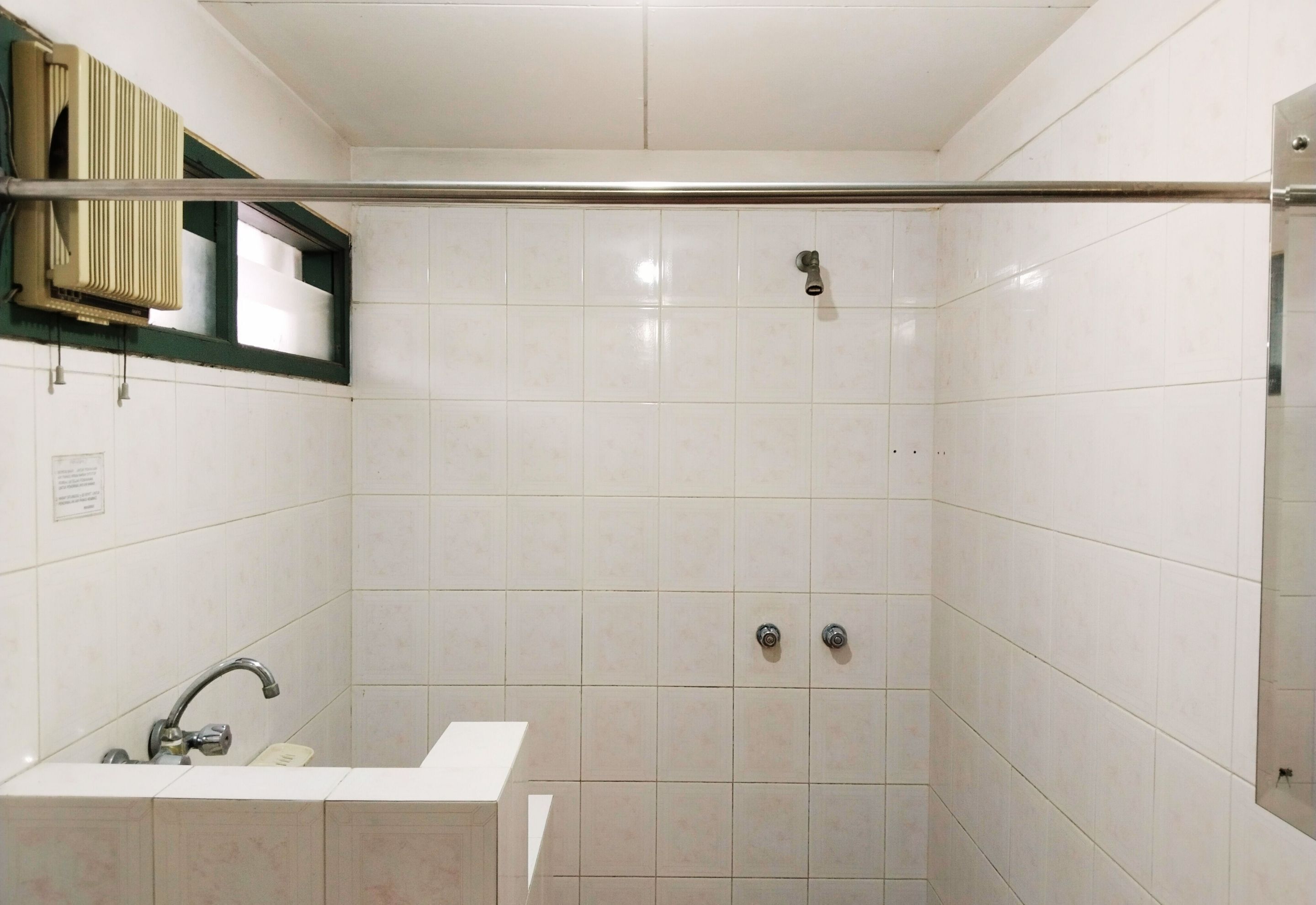Un baño con azulejos blancos, un lavamanos y una zona de ducha.