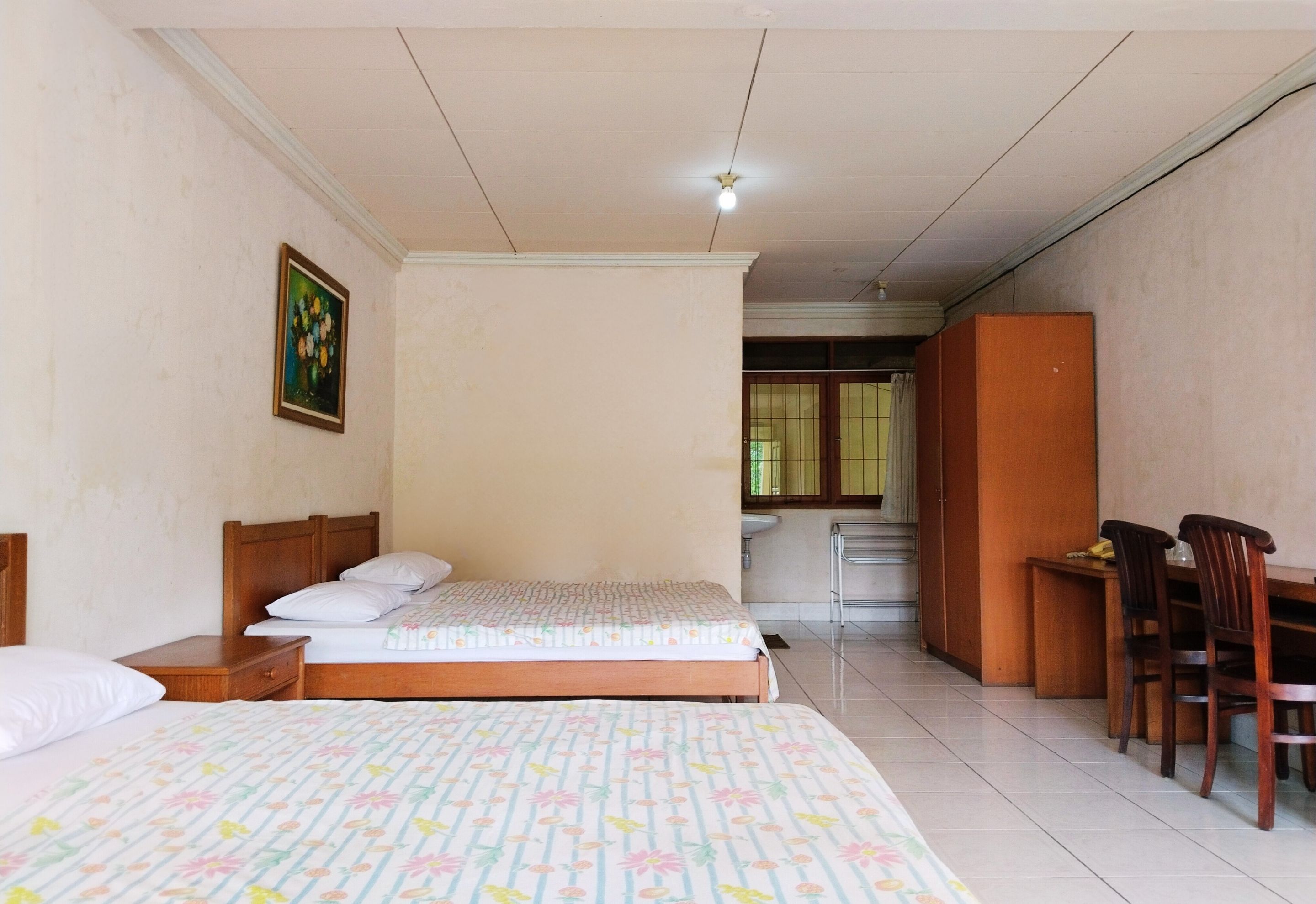 A hotel room with two beds, a desk, and a chair.