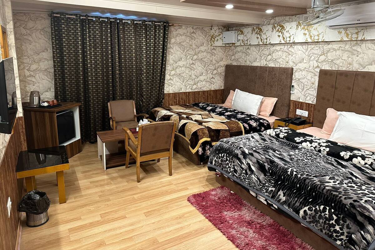 A hotel room with two beds, a desk, a chair, a TV, and a red rug.