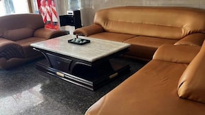 A modern living room with a brown leather sofa, a marble coffee table, and a black entertainment unit.