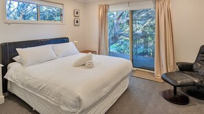 Une chambre à coucher avec un lit, une chaise, une fenêtre et une vue sur les arbres.