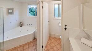Une salle de bain avec une baignoire, des toilettes et une fenêtre.