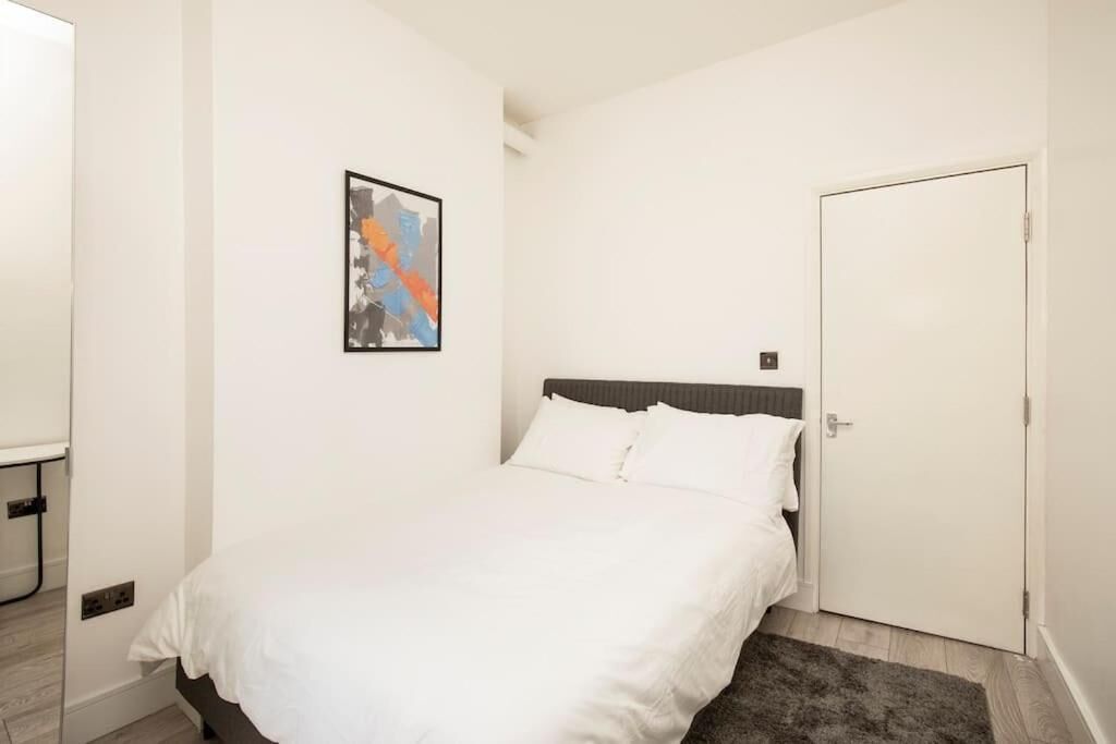 Une chambre à coucher avec un lit, une porte et une œuvre d’art accrochée au mur.