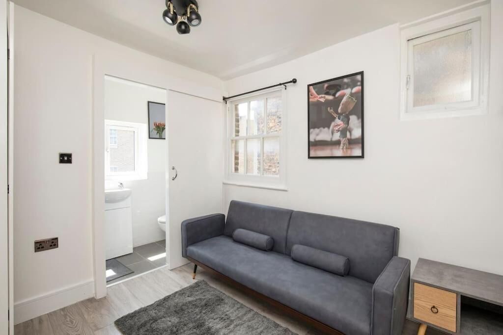 Een moderne woonkamer met een grijze bank, een klein bijzettafeltje en een raam met uitzicht.
