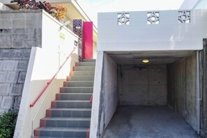 Una escalera de concreto conduce a una entrada cubierta con barandilla de metal.