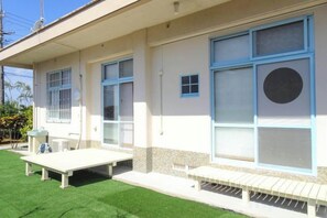 A building with large windows, a flat roof, and a small outdoor seating area. - Minshuku Itoman Bettei Goyukkuri (Itoman)