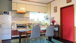 Een kleine keuken met witte kasten, een magnetron, een broodrooster en een eettafel met twee stoelen.