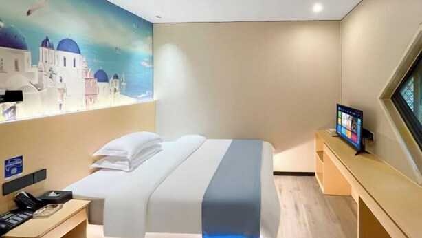 A hotel room with a bed, a desk with a phone, a TV, and a wall mural. - Tianshun Hotel (Guangzhou ERGONG subway station store) (Guangzhou)