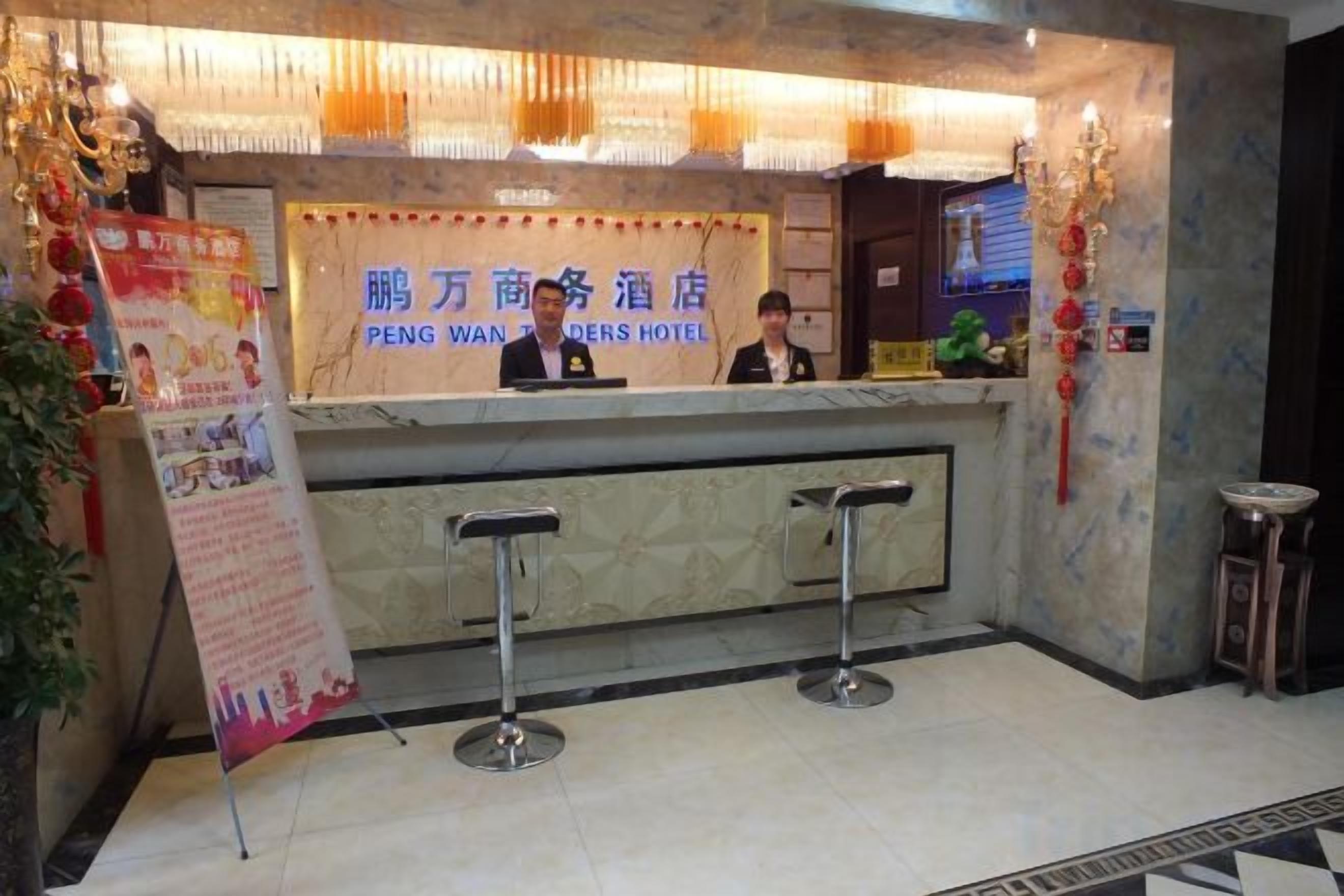 A hotel reception desk with a sign, two bar stools, and a decorative wall.