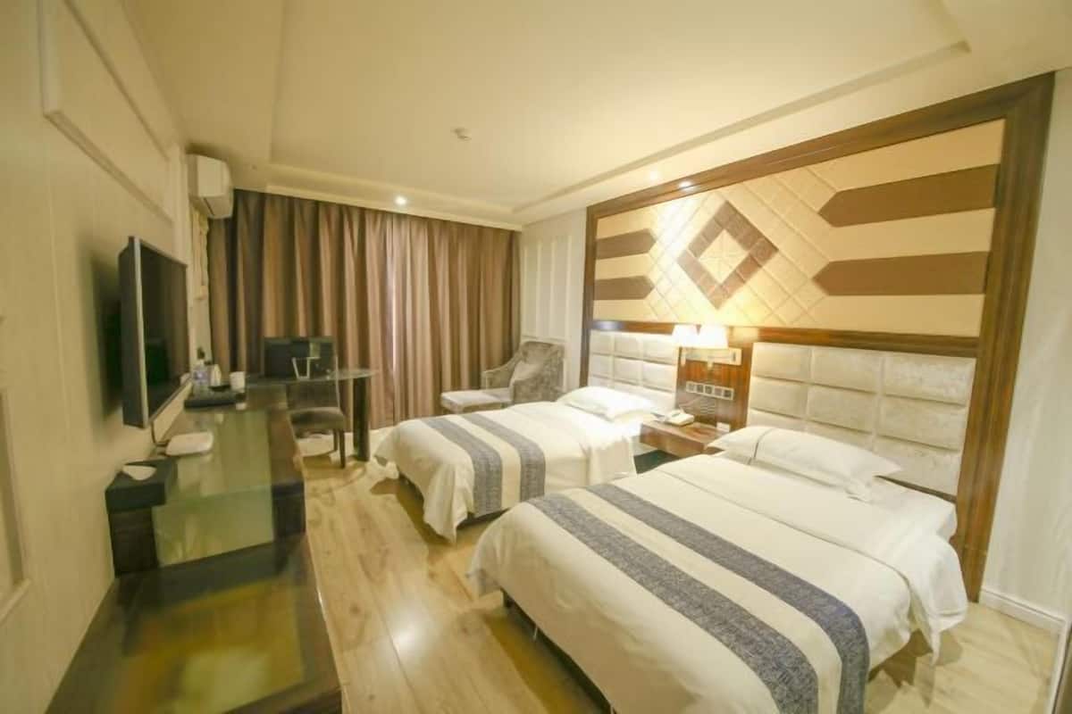 Habitació d'hotel amb dos llits, un televisor, un escriptori i un ampli mural decoratiu.