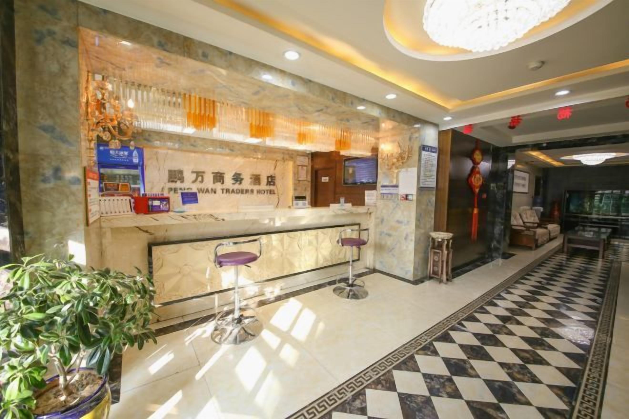 Zona de recepción de hotel con mostrador de mármol, dos taburetes, una planta en maceta y suelo a cuadros.