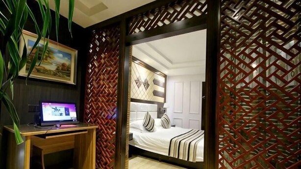 Un dormitorio con cama, escritorio y computadora.