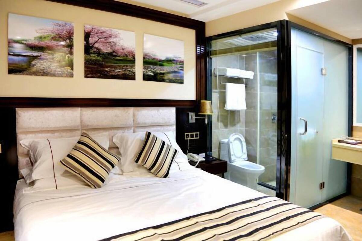Habitació d'hotel amb llit, dutxa tancada amb vidre i vàter fixat a la paret.