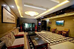 A lobby with a checkered floor, sofas, a TV, and a painting on the wall.