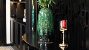 A black table with a green vase of flowers and a candle. - YO Hotel (Hai Phong)