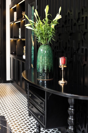 A black table with a green vase of flowers and a candle. - YO Hotel (Hai Phong)