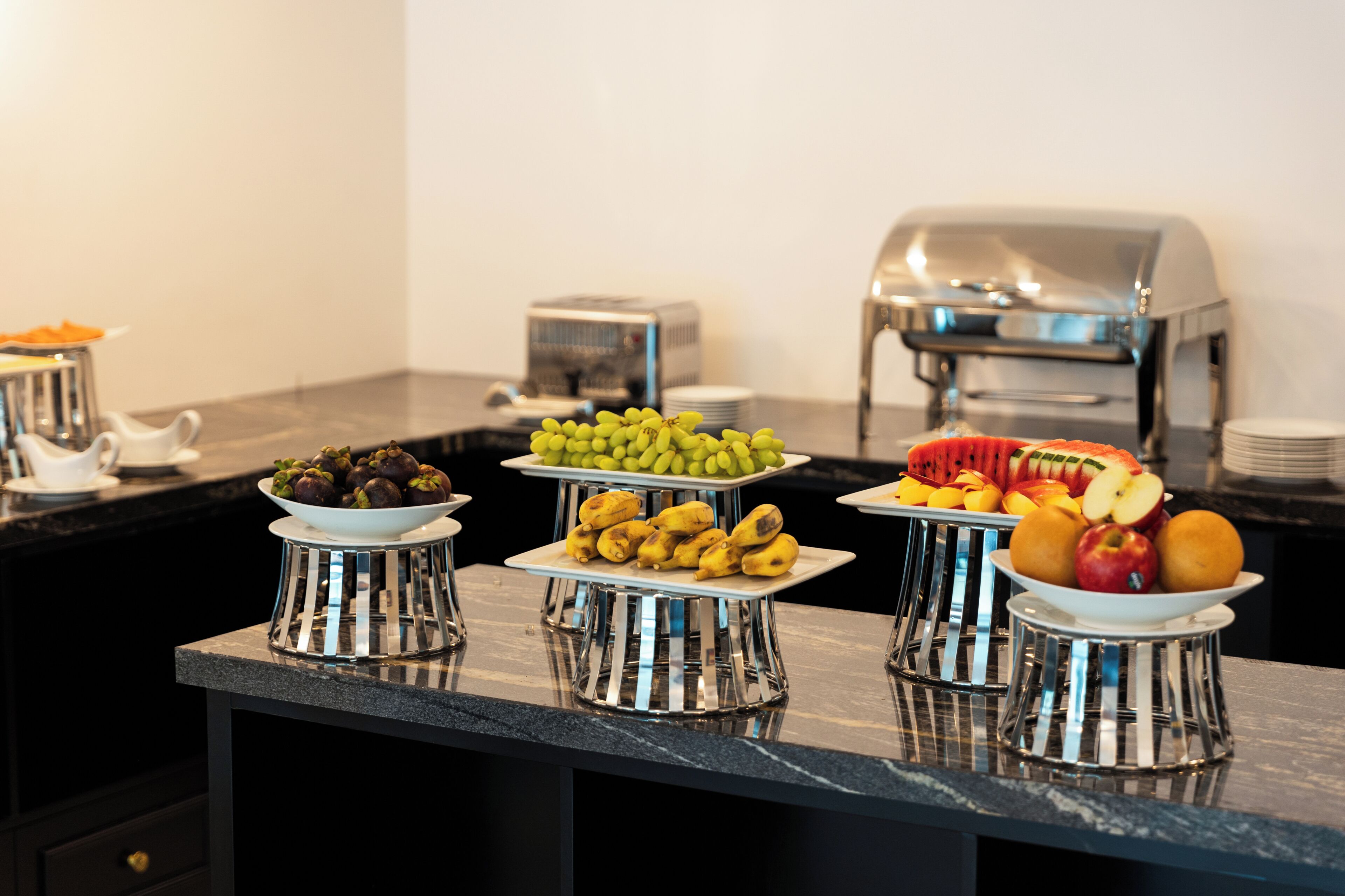 Una mesa de buffet con diversas frutas y un tostador.