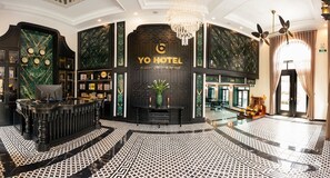 Eine Lobby mit einer Rezeption, einer großen Uhr und einem Schild mit der Aufschrift 'YO HOTEL'.