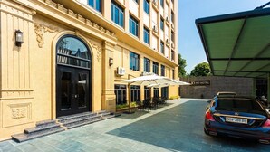 A hotel entrance with a black door, outdoor seating, and a parked car. - YO Hotel (Hai Phong)