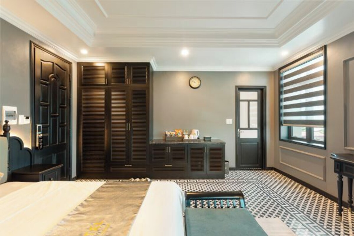 A bedroom with a bed, a wardrobe, a desk, and a window with blinds.