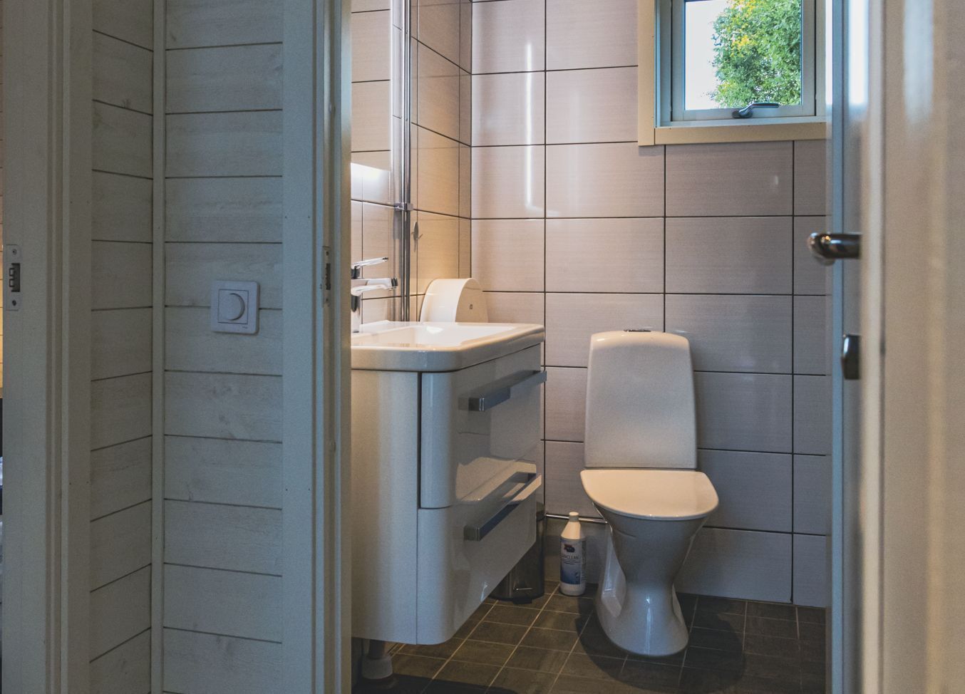 Un baño con inodoro, lavamanos y armario de almacenamiento.