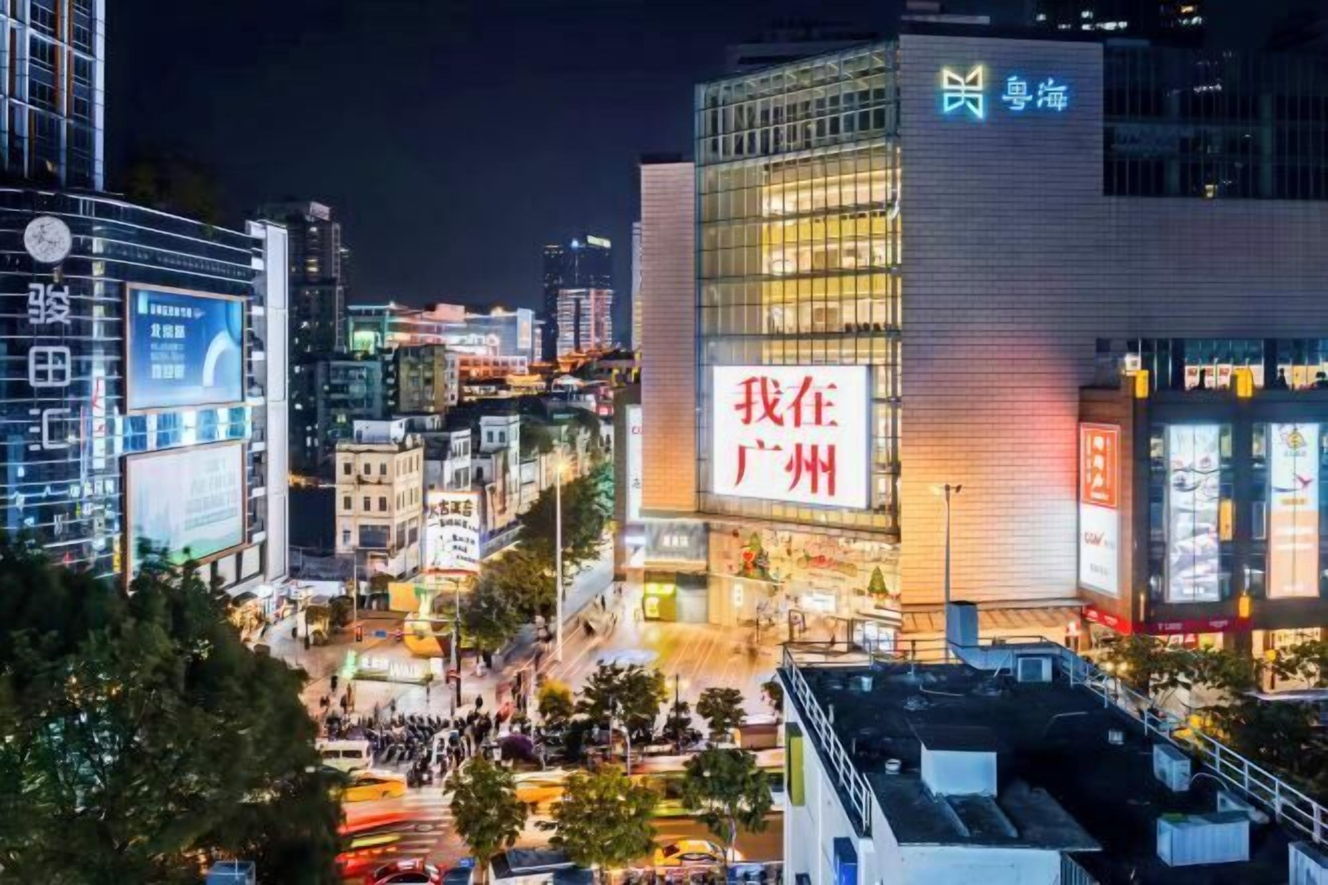A busy urban street at night with illuminated buildings and billboards.
