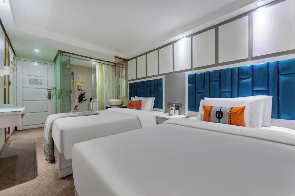 A hotel room with two beds, a desk, and a bathroom.