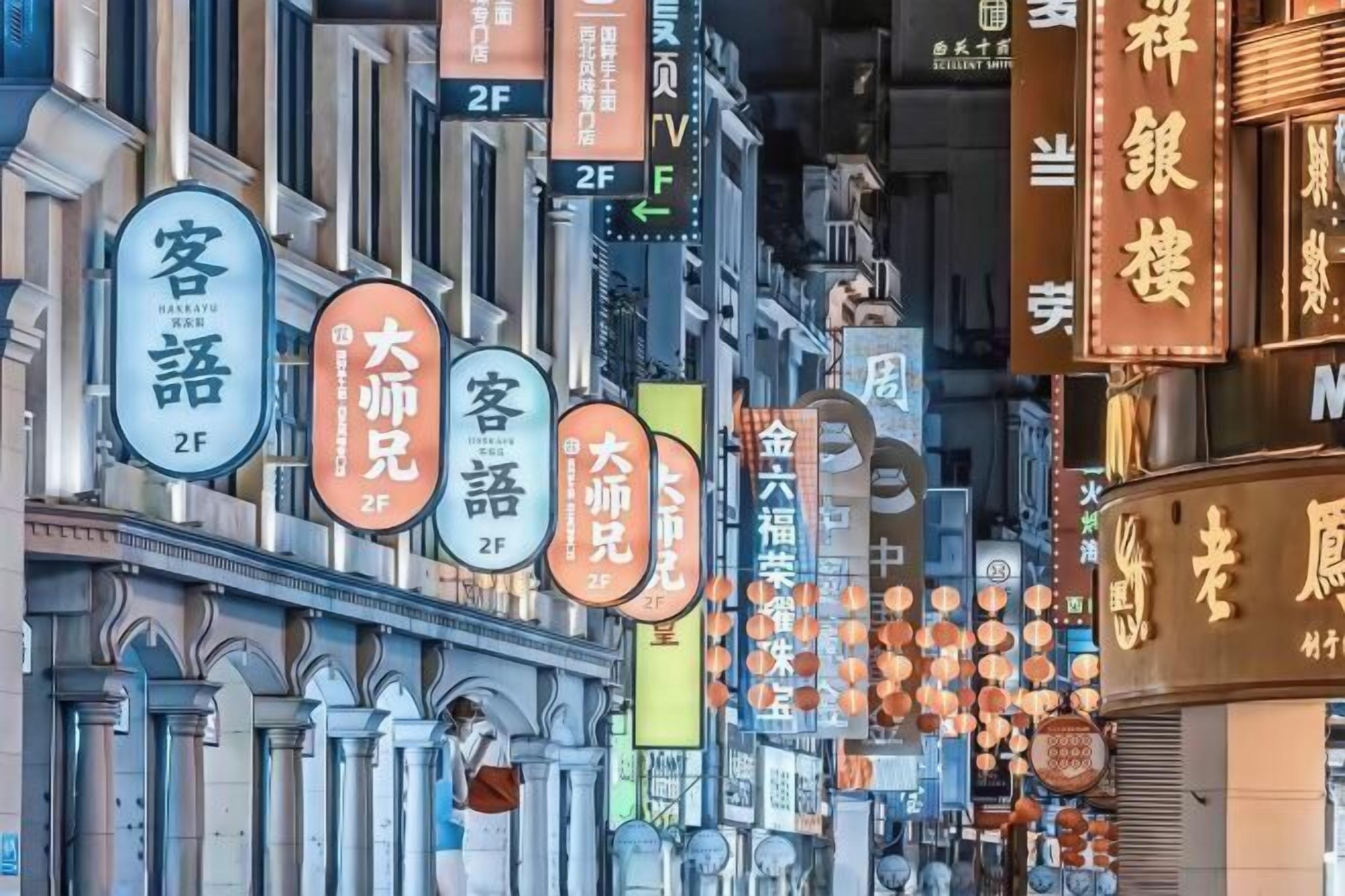 A street lined with traditional Chinese buildings, each with illuminated signs in Chinese characters indicating various businesses and services.