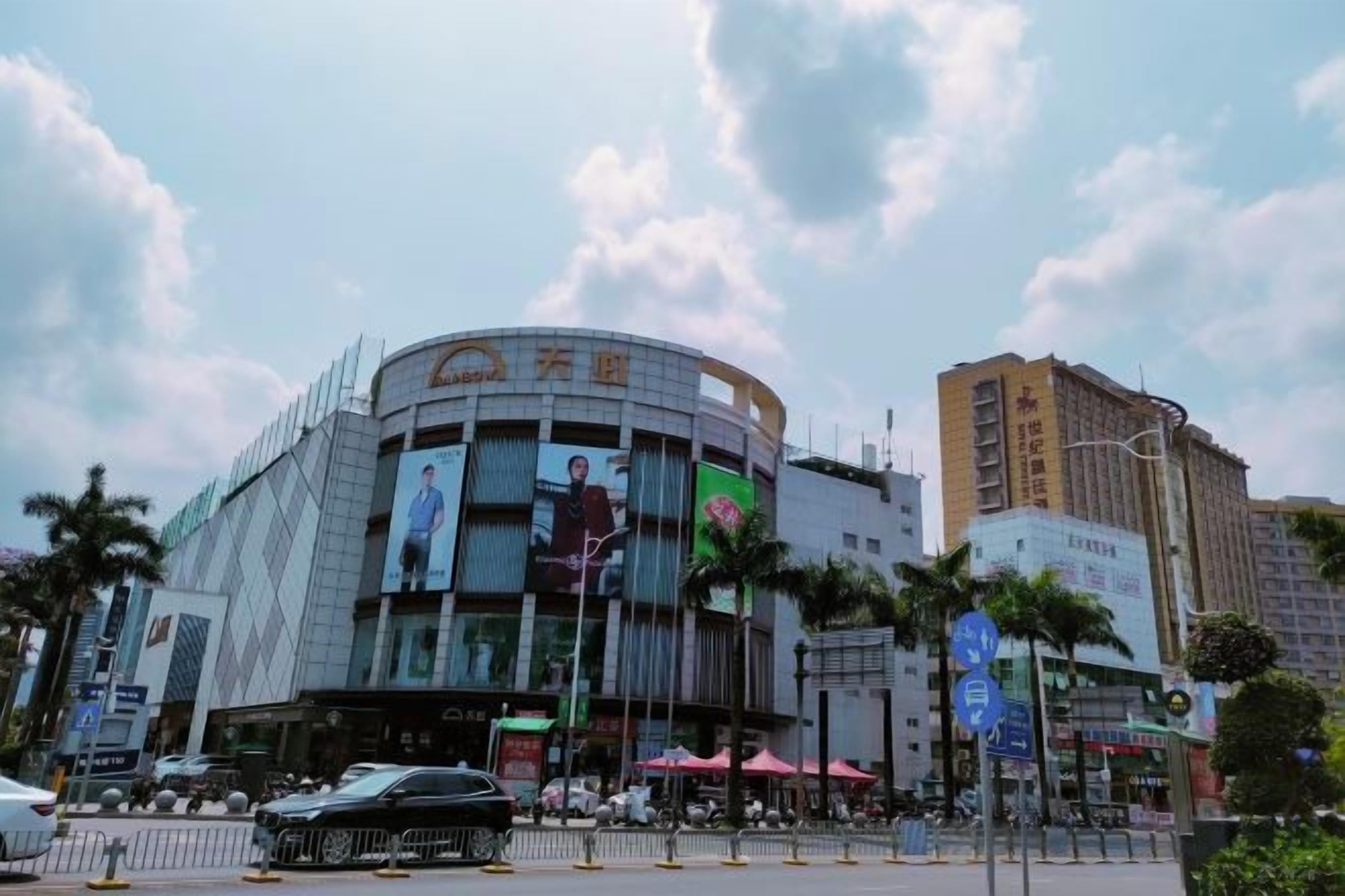 A modern building with a curved facade, large windows, and multiple advertisements.