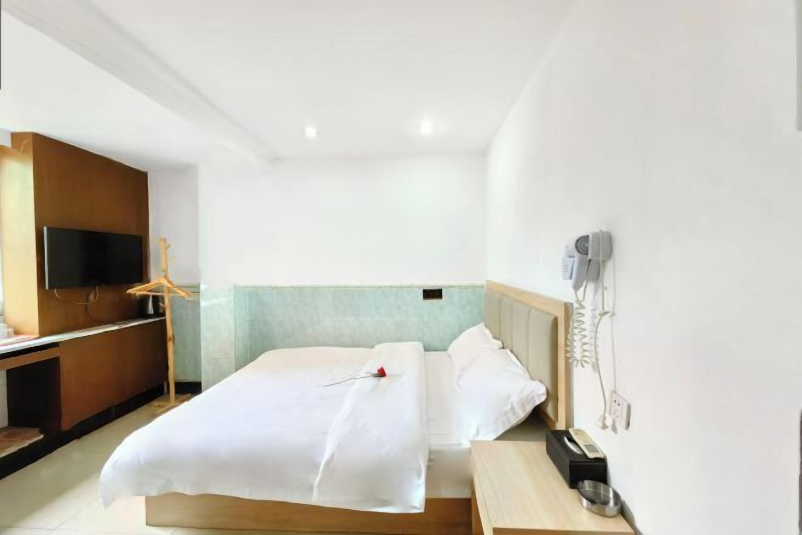 Quarto de hotel com cama, televisão, escrivaninha e telefone.